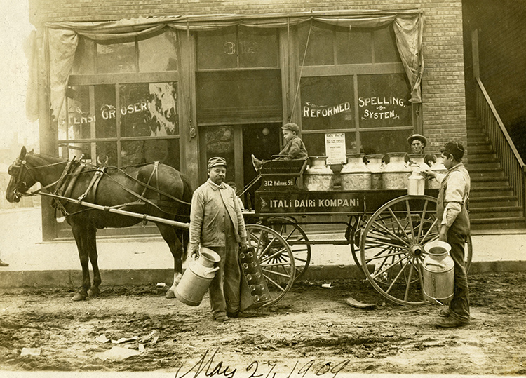 Nikoles Aleshi (center-left) with helpers outside his grocery store at 312 Holmes Street, 1909.